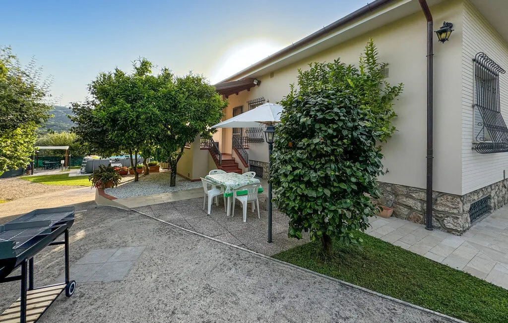 An outdoor patio beside a house, with seating and leafy plants.