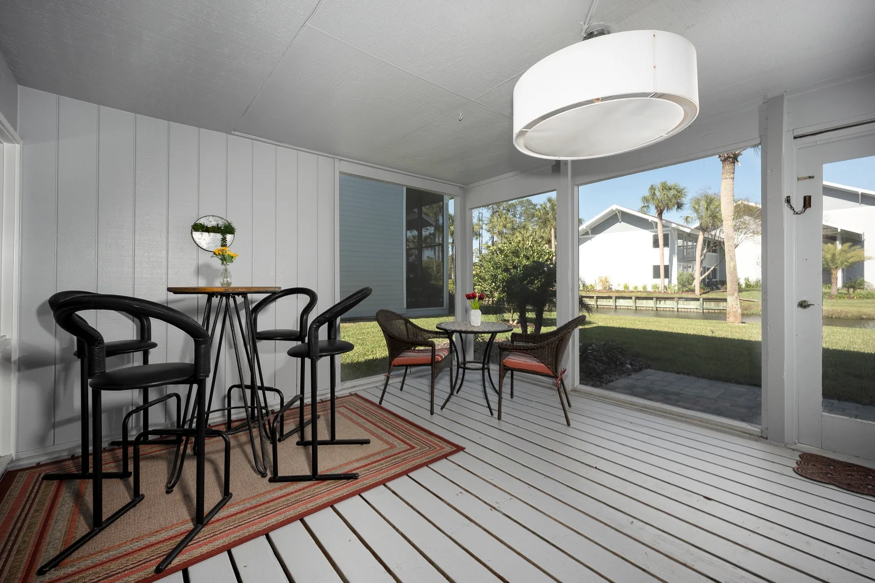 Un patio cerrado y luminoso con mesa de comedor y asientos junto a grandes ventanales.