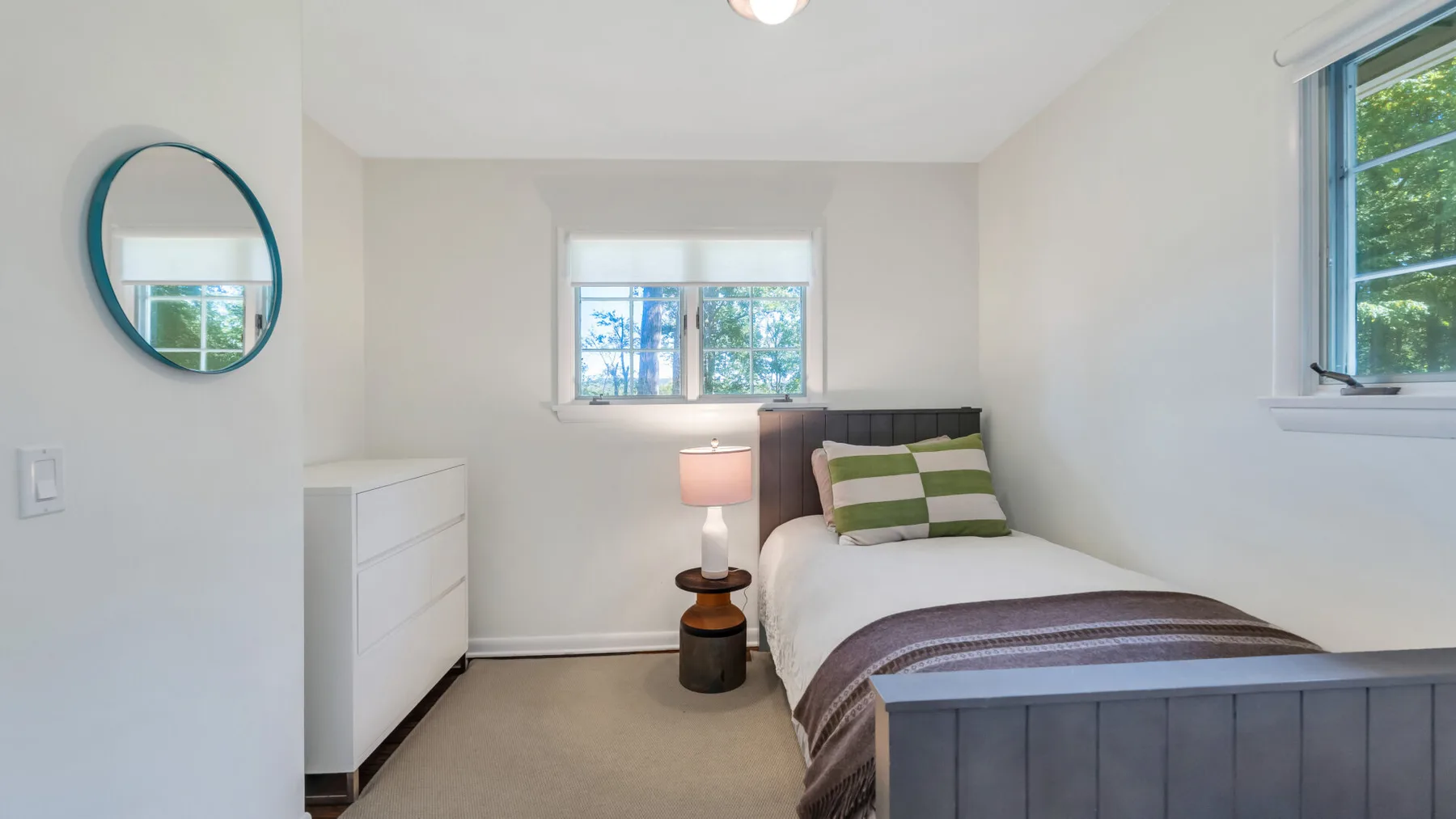 A bedroom with a bed, a small bedside table, and a dresser.