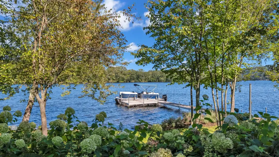 A leafy lakeshore frames a wooden dock extending over the water.