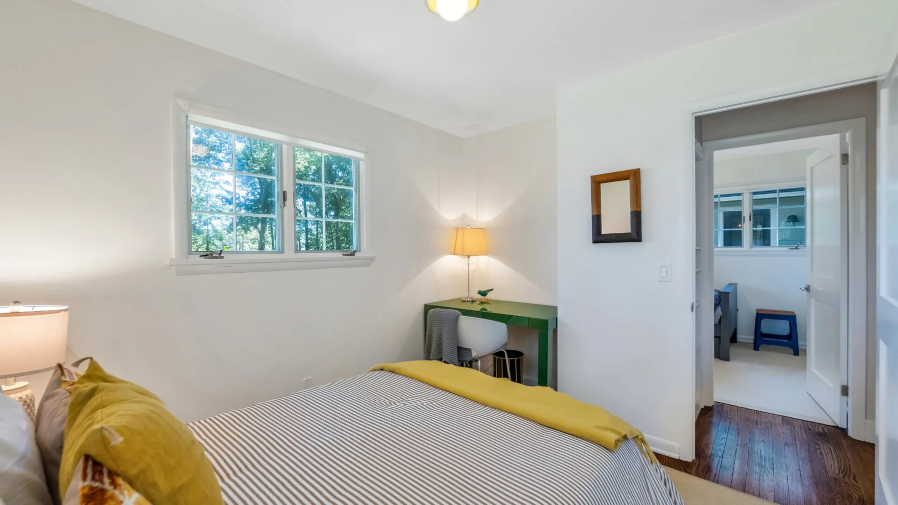 A bedroom with a bed, a window, and a small desk.