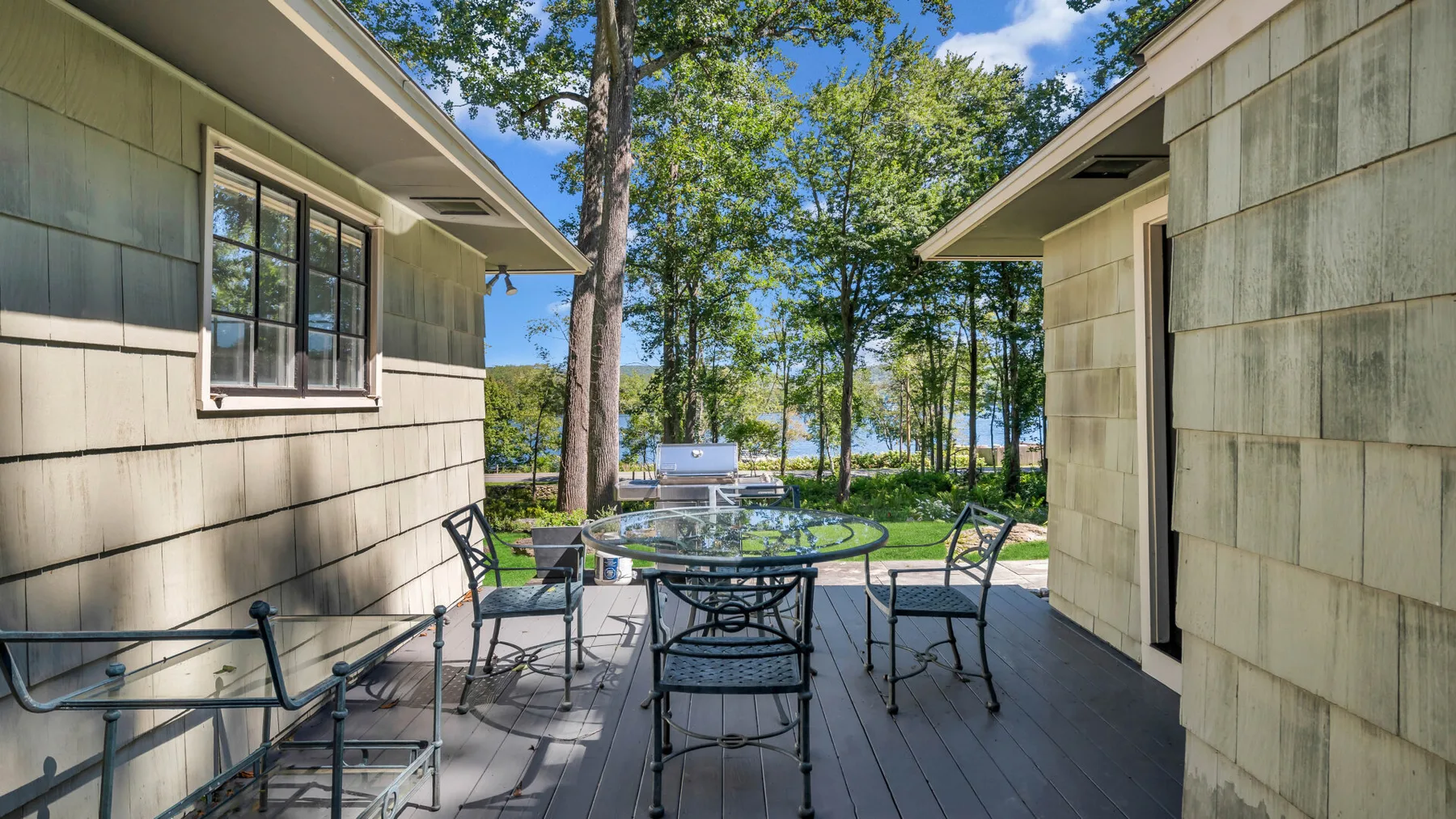 An outdoor dining area sits between two buildings, with trees visible beyond.