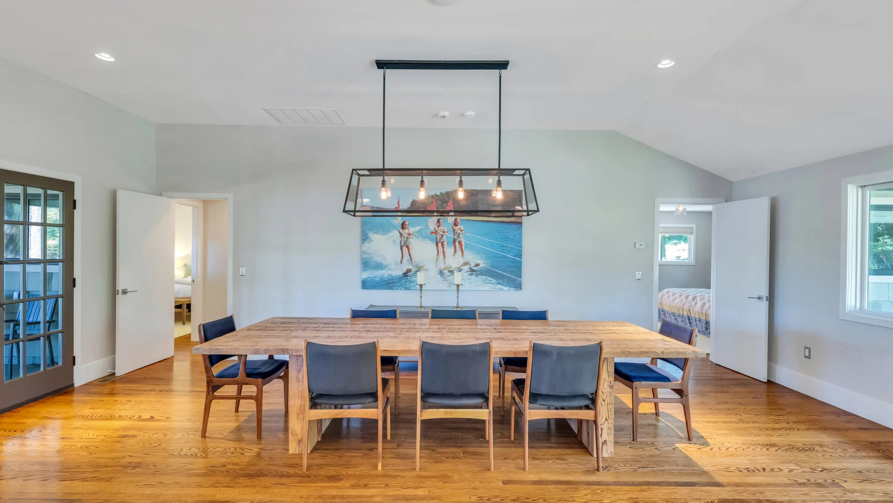 A dining room with a long wooden table beneath a pendant light.