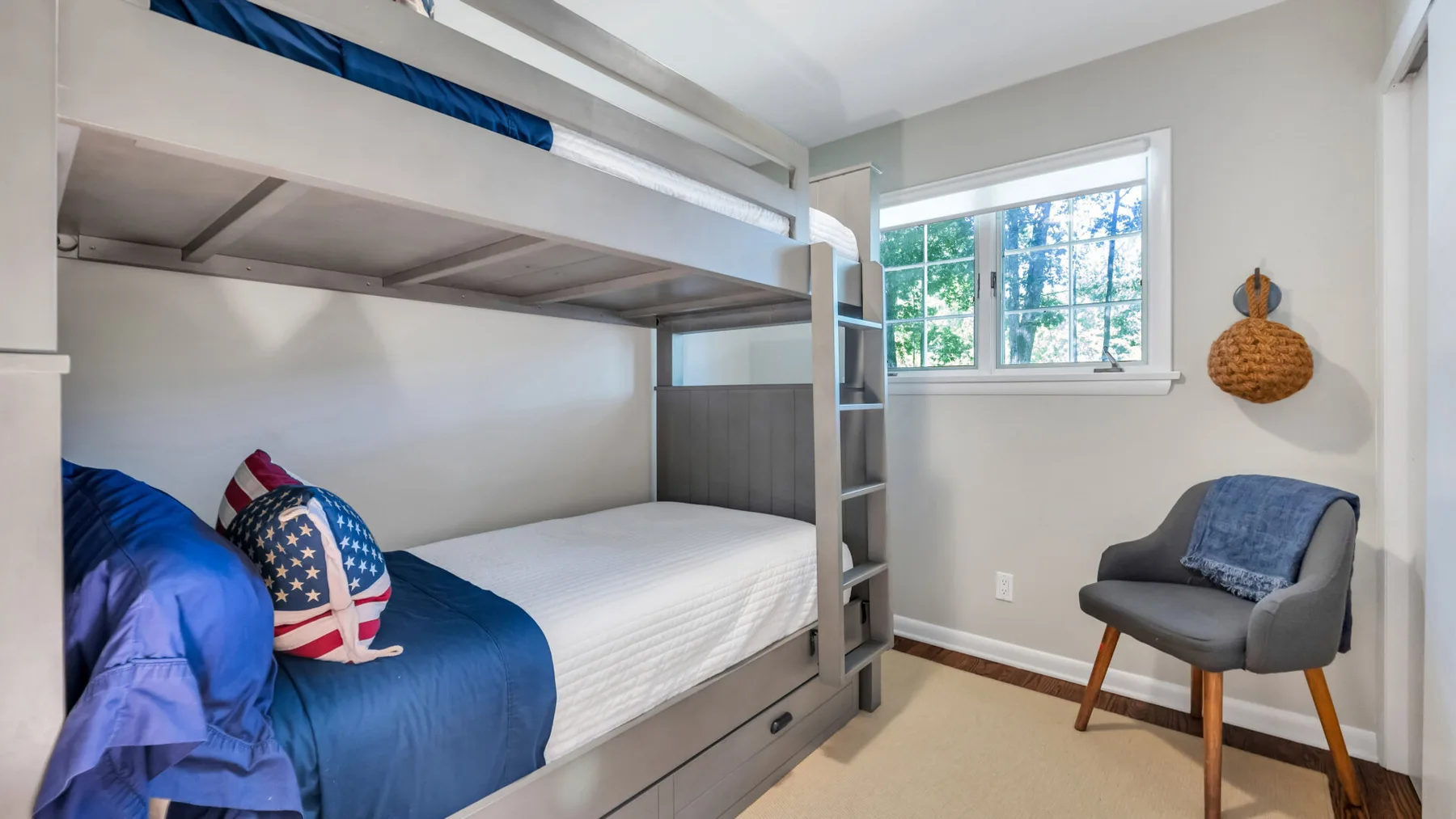 A bedroom with a bunk bed, a window, and a chair.