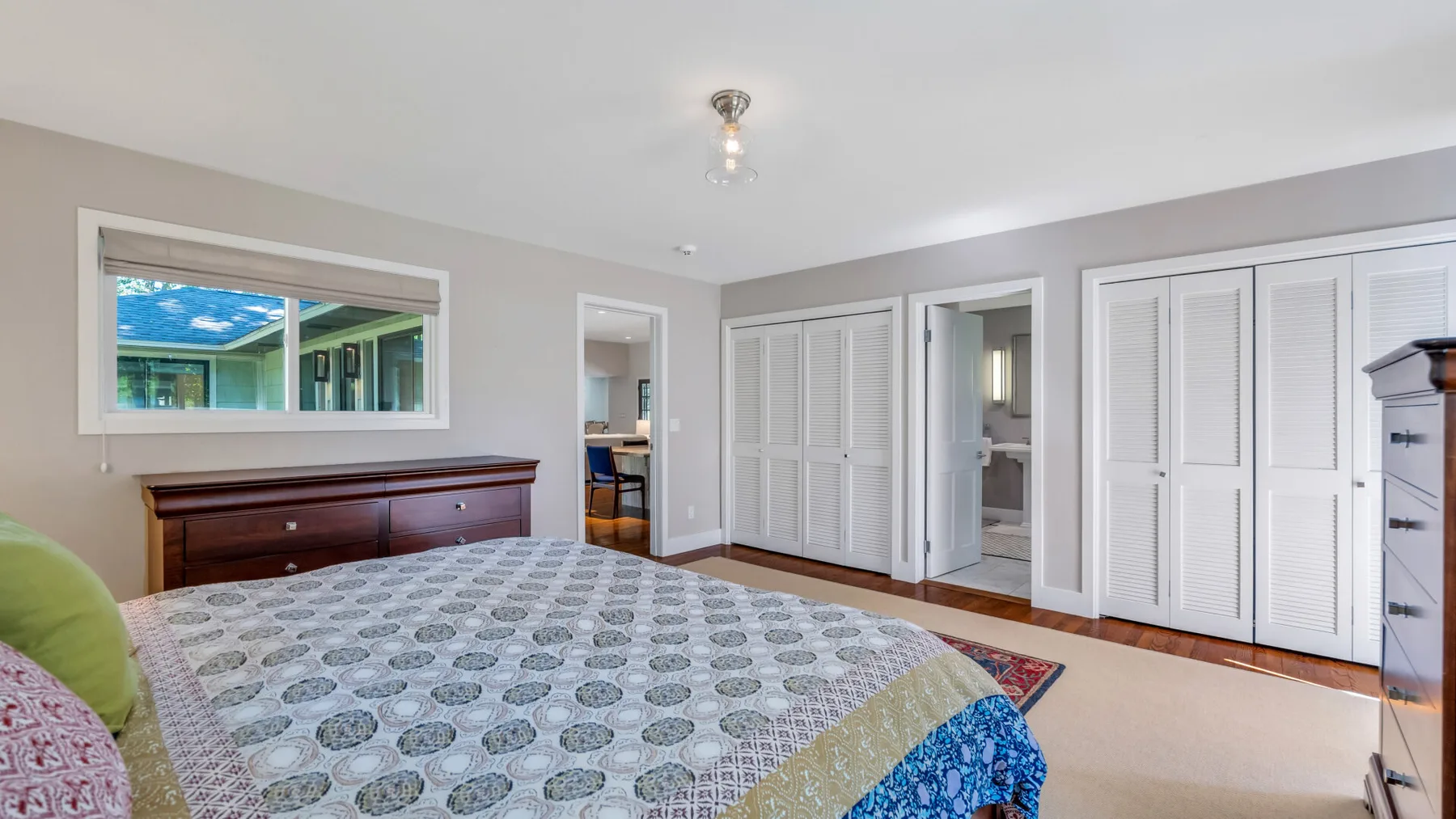 A bedroom with a patterned bedspread and white closet doors.