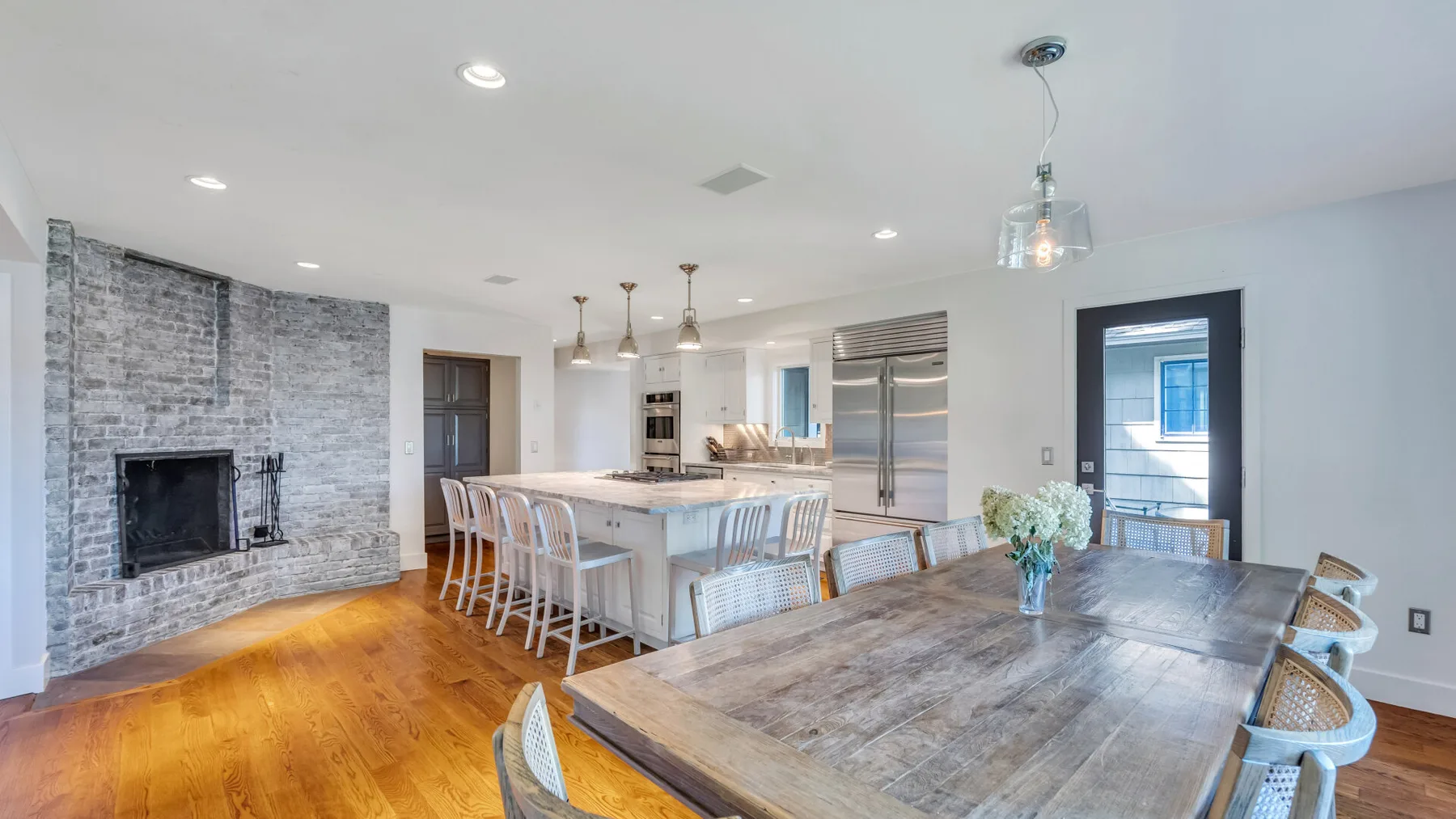 An open dining area features a large wooden table and a kitchen island.