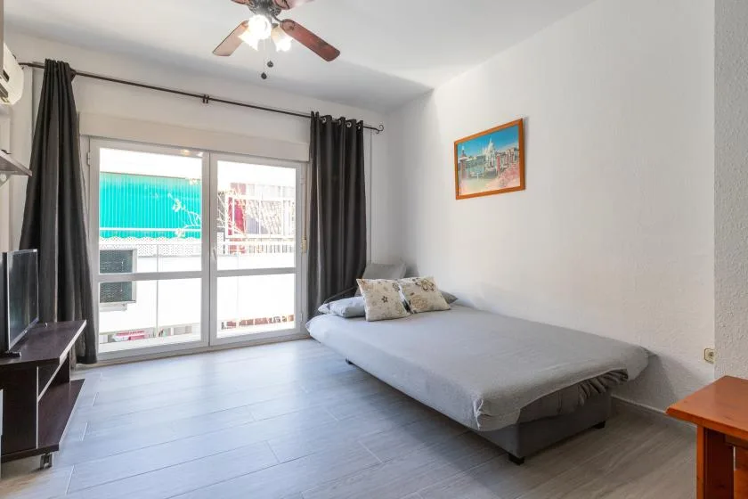 A simple bedroom with a low bed beside bright sliding glass doors.