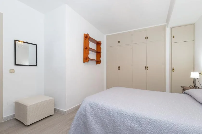 Bedroom with a bed, built-in wardrobes, and a small wall shelf.