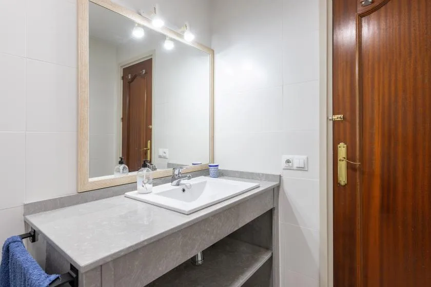 A bathroom vanity with a sink, countertop, and large wall mirror.