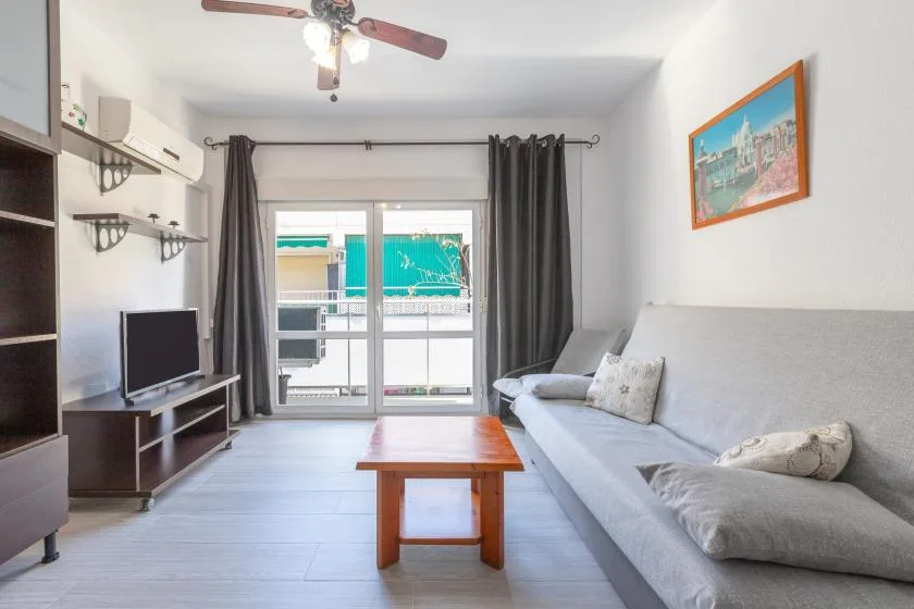 A living room with seating, a coffee table, and glass doors opening to a balcony.
