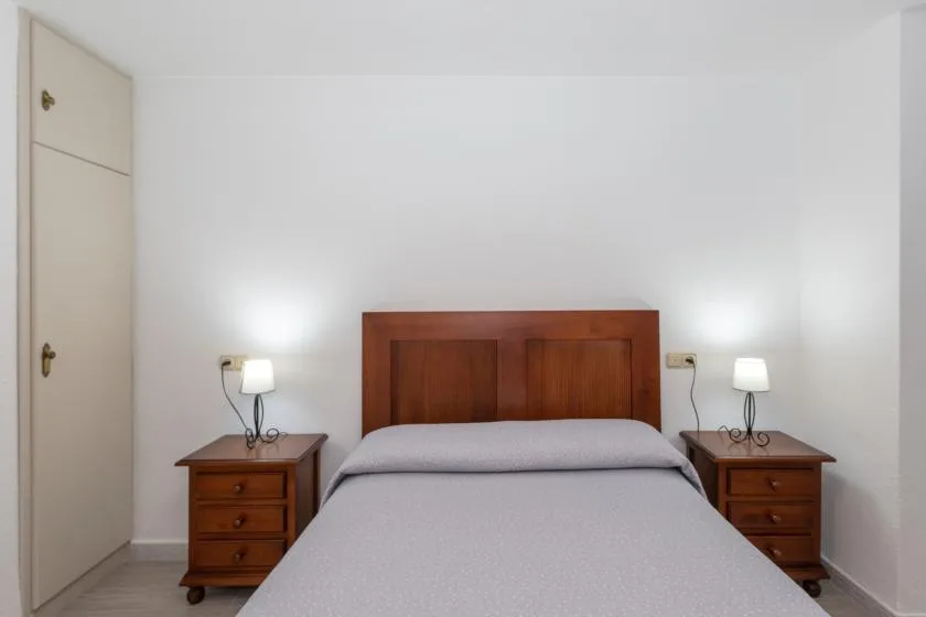 A bedroom with a bed between two wooden bedside tables.