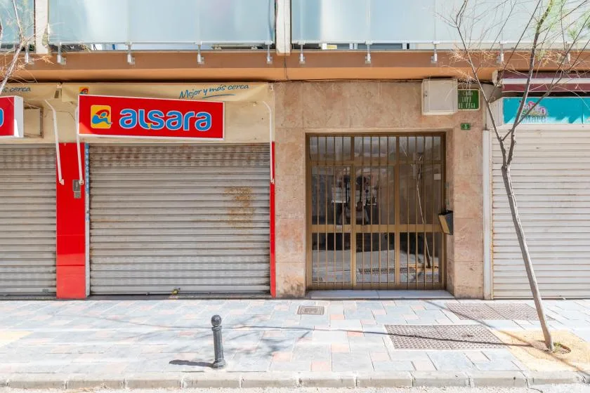 A street-level storefront with closed metal shutters and a barred entrance.