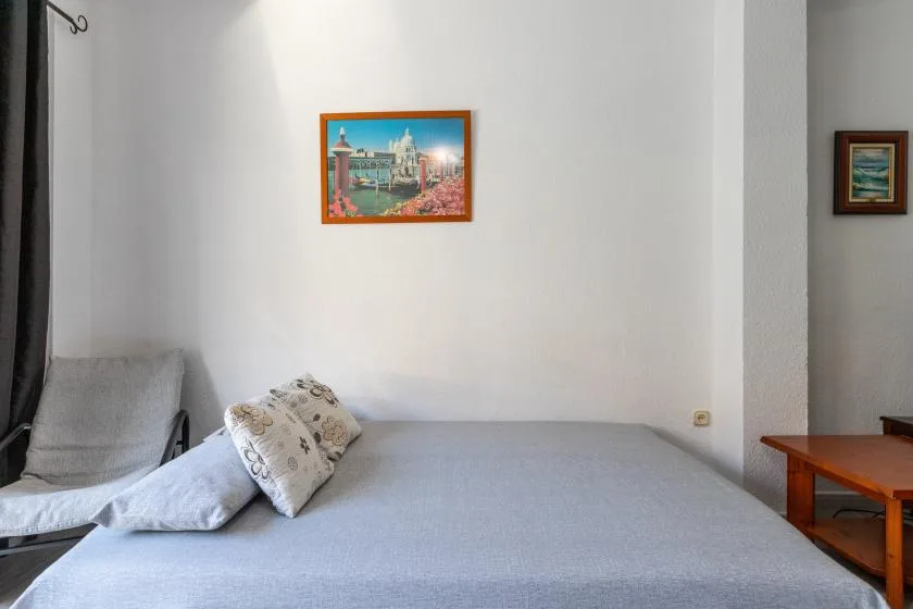 A bedroom with a bed, decorative pillows, and framed wall art.