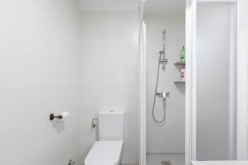 A bright bathroom with a toilet and a glass-enclosed shower.
