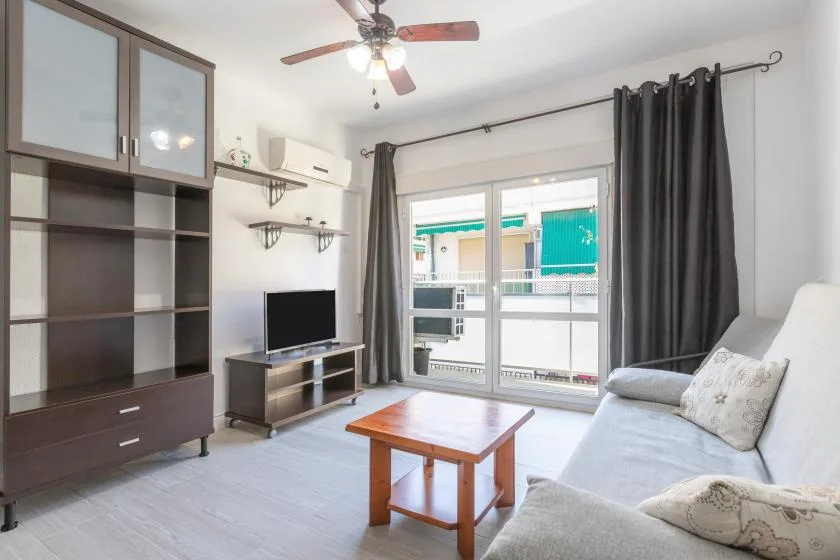 A living room with a television, coffee table, and seating beside a sliding glass door.