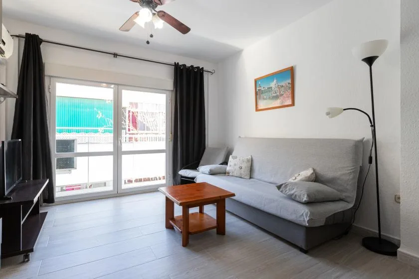 A living room with a gray sofa, wooden coffee table, and glass doors.