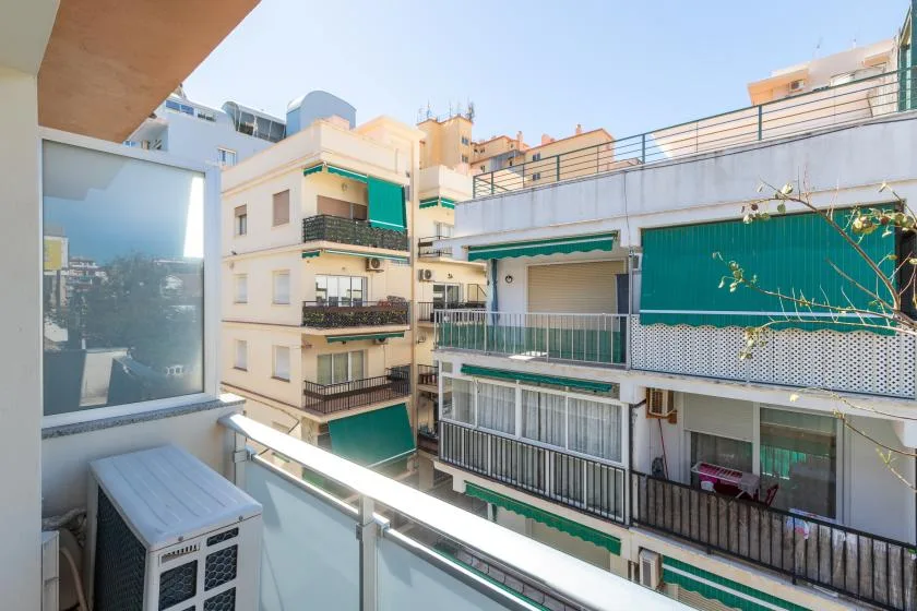 A balcony overlooks nearby apartment buildings with green awnings.