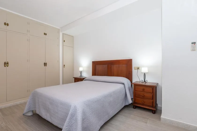 A bedroom with a bed, wooden headboard, and bedside tables.