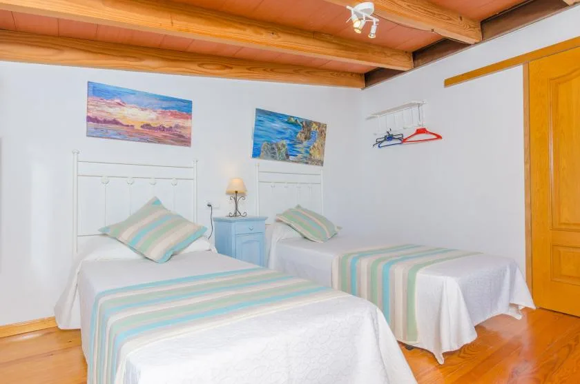 A bedroom with two single beds, striped bedding, and artwork on the walls.