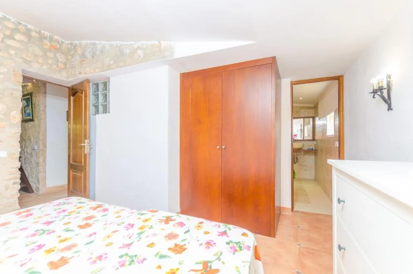 A bedroom with a floral bedspread and a wooden wardrobe.