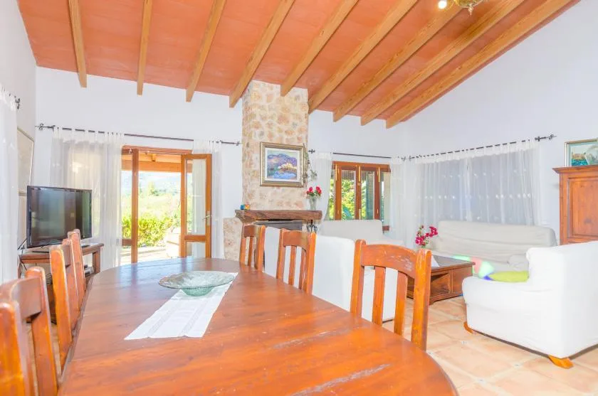 A bright dining and living area with a wooden table and white seating.