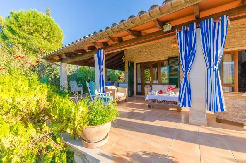 A covered outdoor patio with blue-and-white curtains and seating.