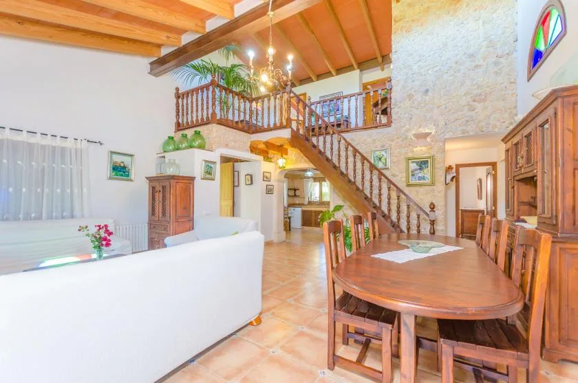 A spacious living and dining room with a staircase and wooden dining table.