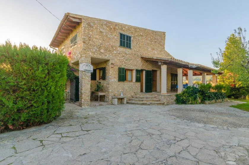 A stone house with a covered entrance and a paved courtyard.