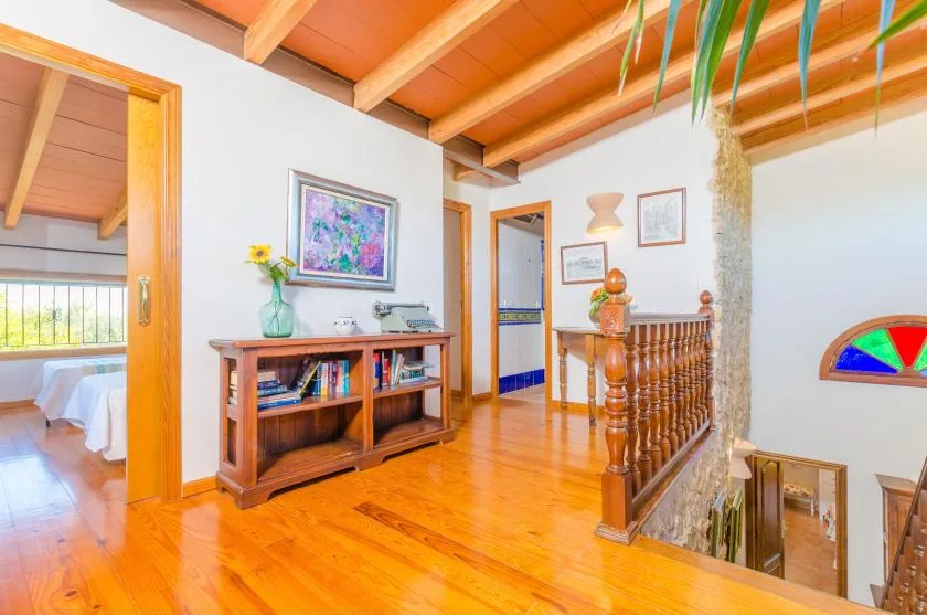 A wood-floored interior hallway opens onto a landing with a wooden railing.