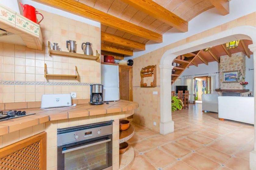 A tiled kitchen with a countertop and oven opens into a living area.