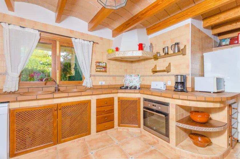 A warm-toned kitchen with wooden cabinets and a window overlooking greenery.