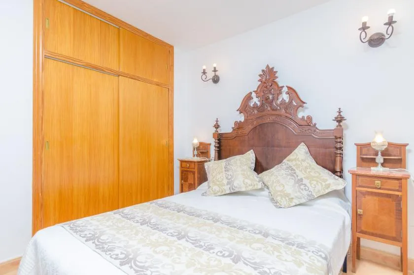 A bedroom with a carved wooden bed and matching bedside tables.