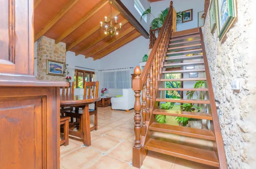 A dining and living area with a wooden staircase and exposed ceiling beams.
