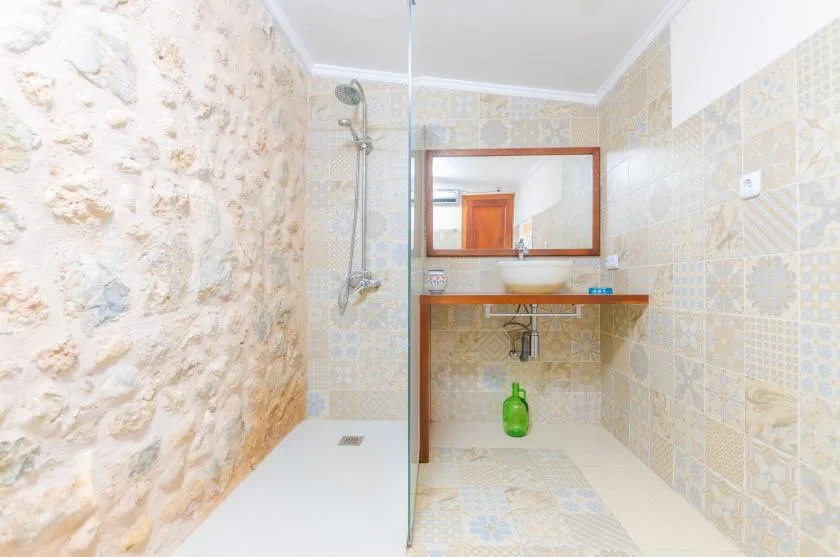 A tiled bathroom with a shower, sink, and wall mirror.