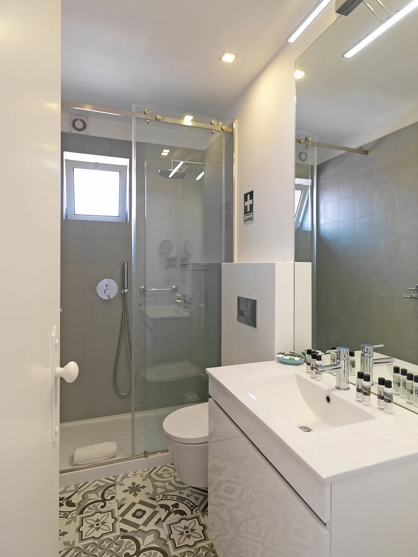 A bathroom with a glass shower, toilet, and white sink counter.