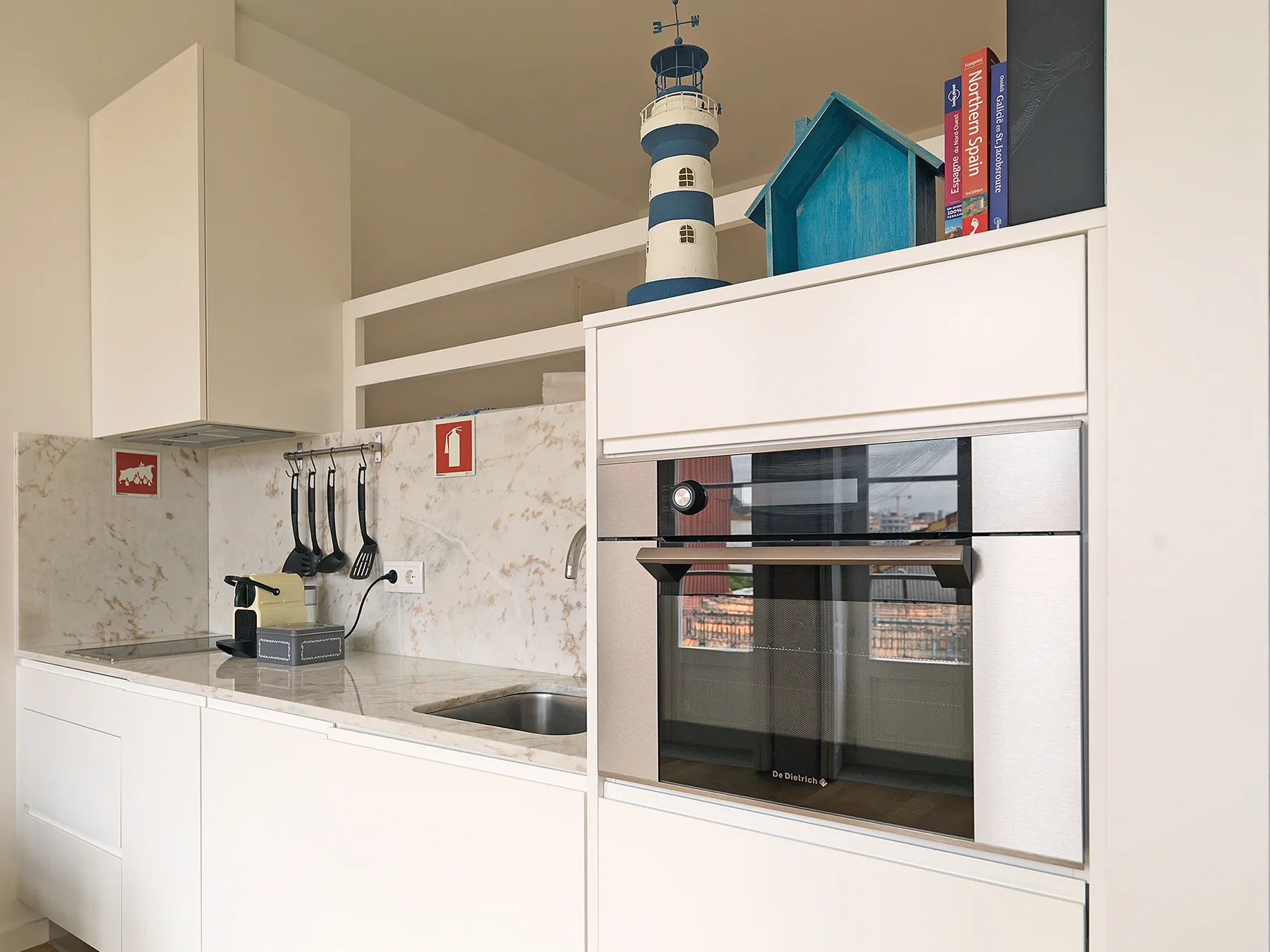 A compact kitchen with white cabinetry, a countertop, and a built-in oven.