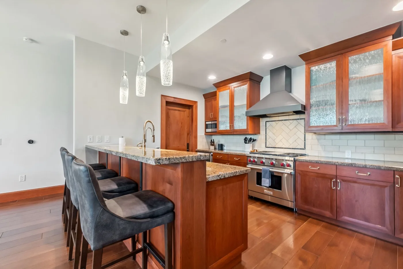 A bright kitchen features a wood island with bar seating and stainless-steel appliances.