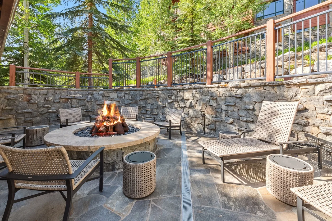 An outdoor patio with a stone fire pit surrounded by seating.