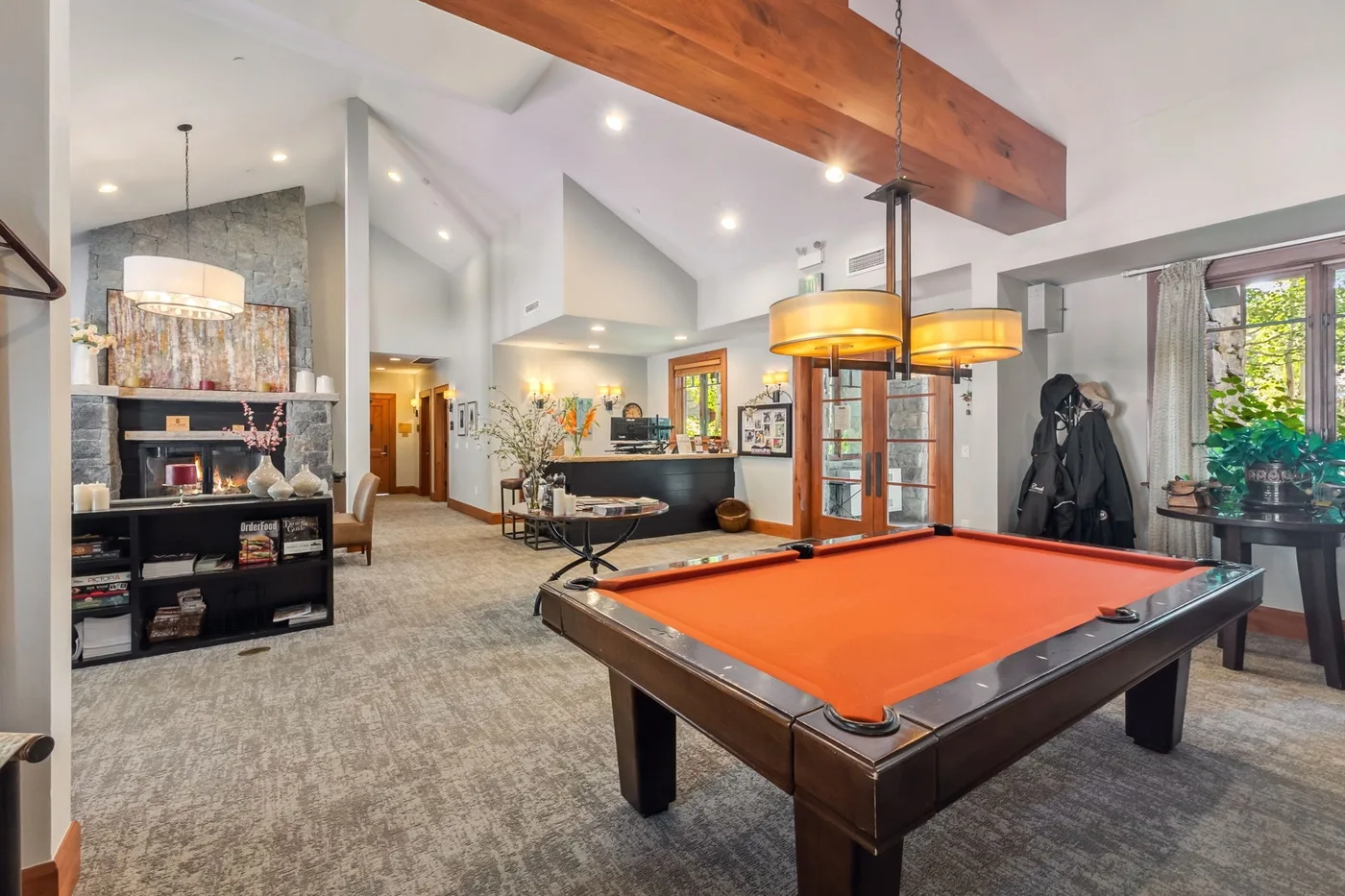 A spacious living area features a pool table beneath exposed wooden beams.