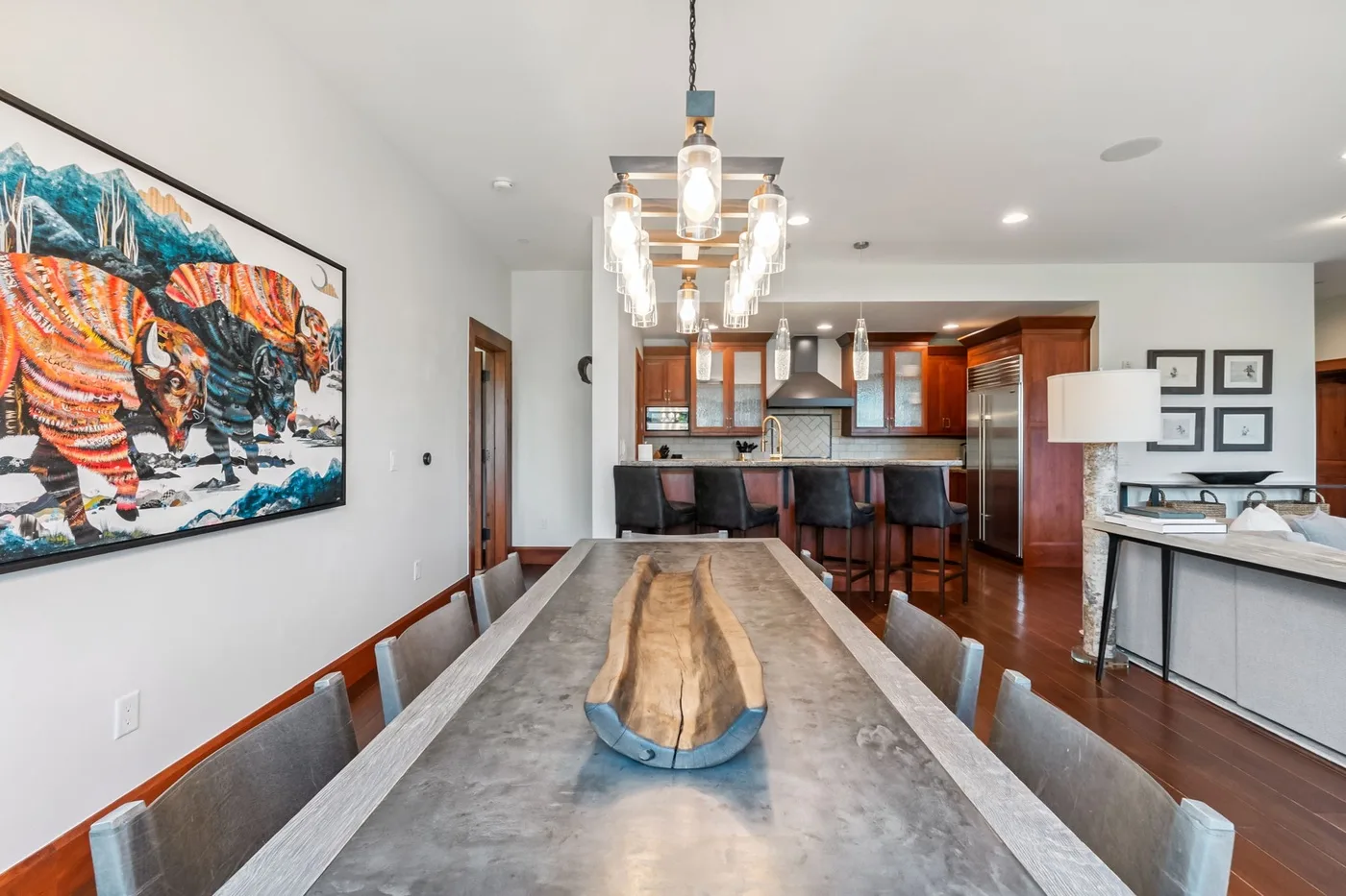 A dining area with a long table and a kitchen in the background.