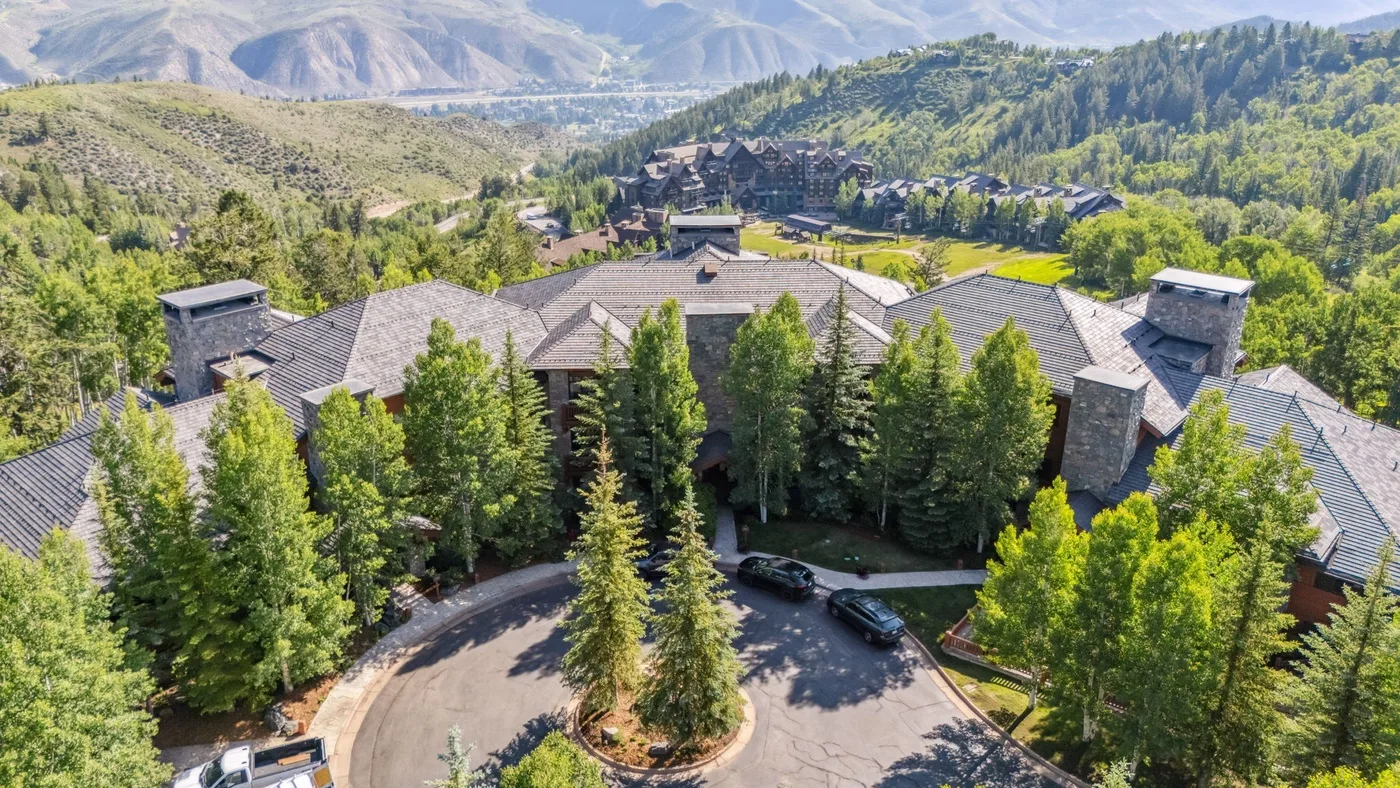 Aerial view of a mountain resort complex surrounded by trees and forested hills.