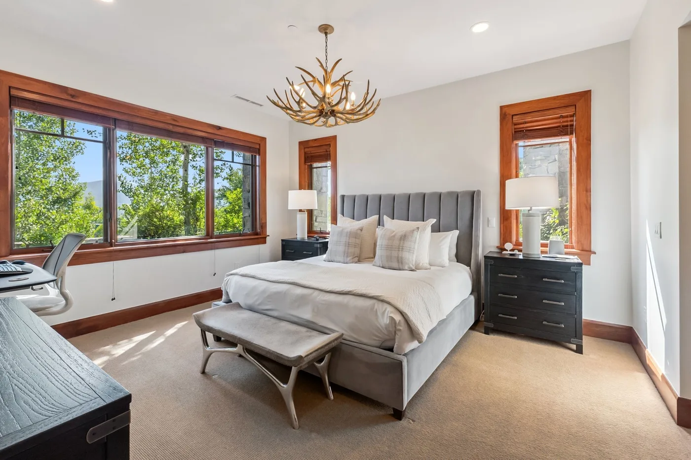 A bedroom with a bed, bedside tables, and large windows.