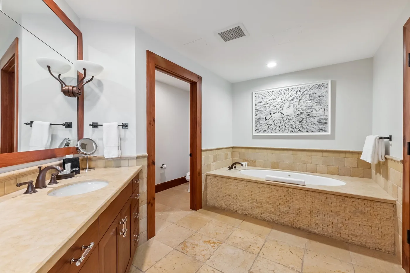 A bathroom with a bathtub, a sink, and a framed wall print.