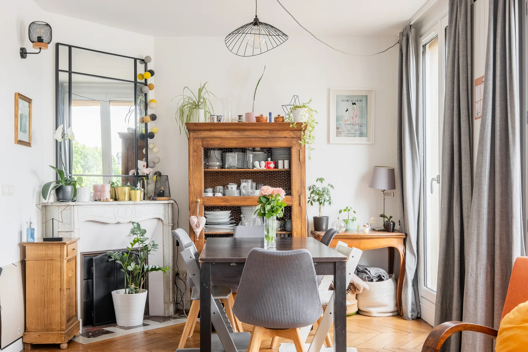 Un comedor y sala de estar con un aparador de madera, una mesa y ventanas grandes.