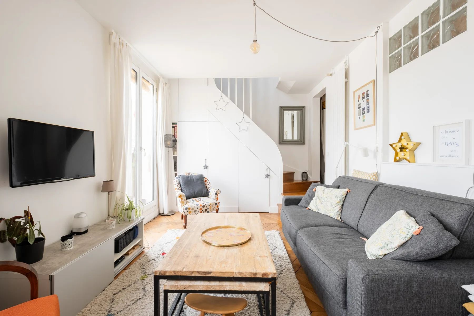 Una sala luminosa con un sofá gris y una mesa de centro de madera.