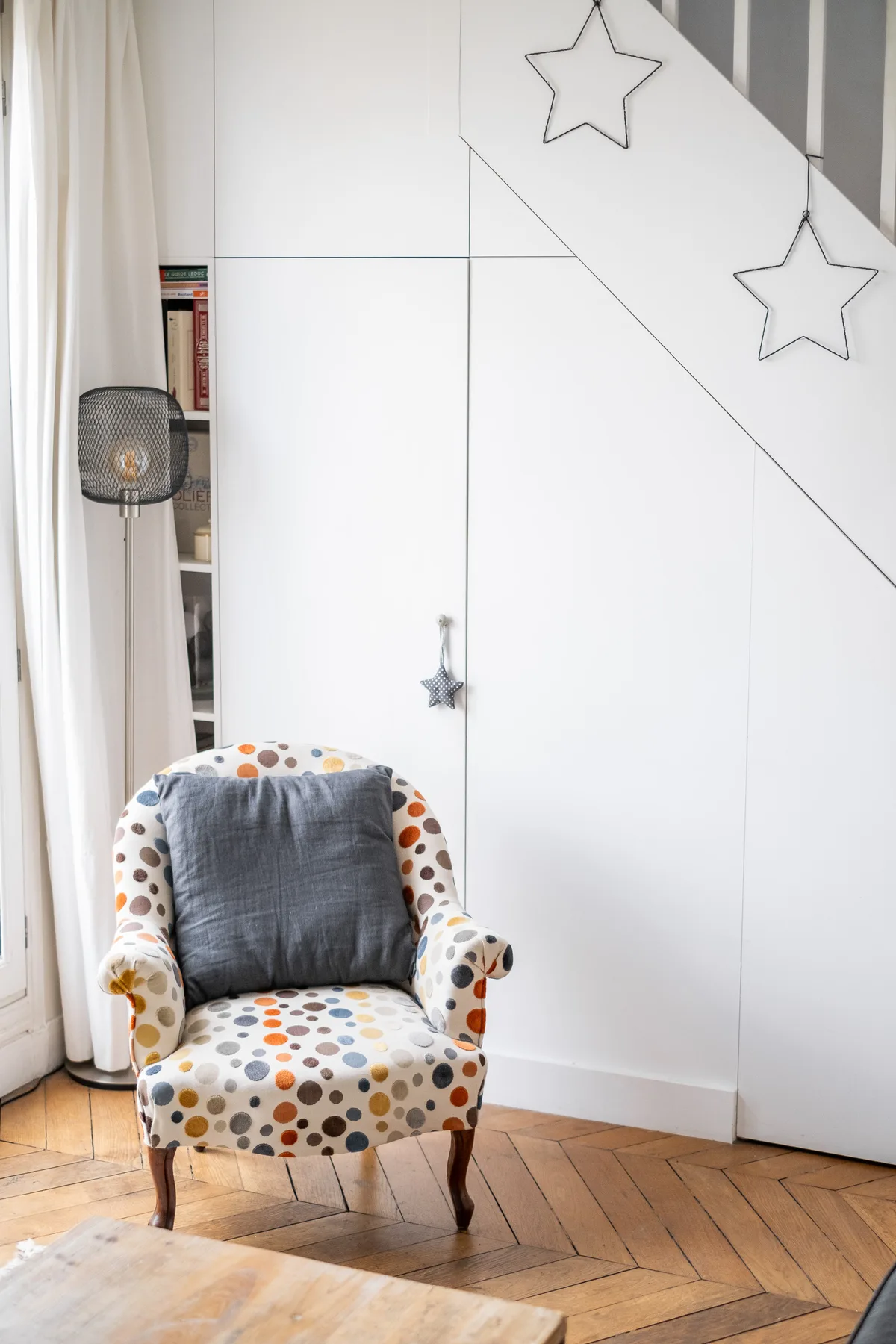 Una luminosa zona de estar con un sillón estampado junto a una ventana con cortinas.