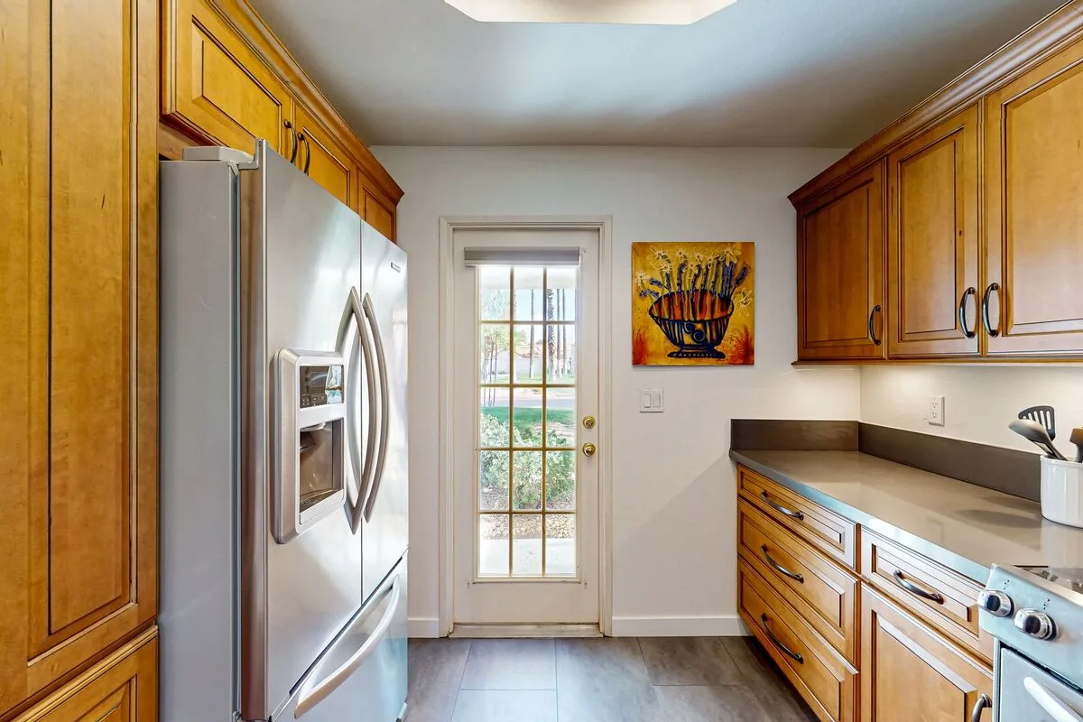 A kitchen with wooden cabinets, stainless steel appliances, and a glass-paneled door.