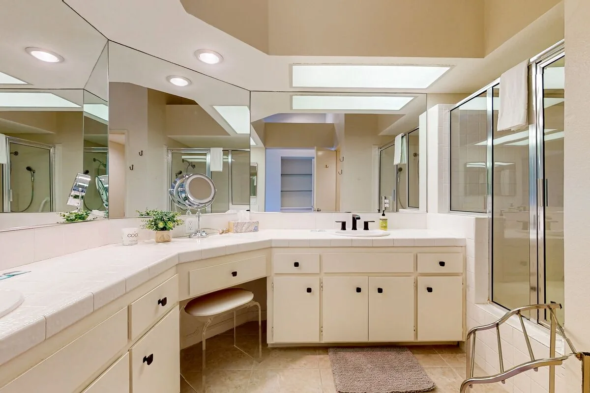 A spacious bathroom with a long vanity, mirrors, and a glass shower.