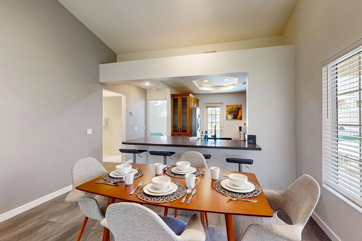 A dining area with a set table and an open kitchen in the background.