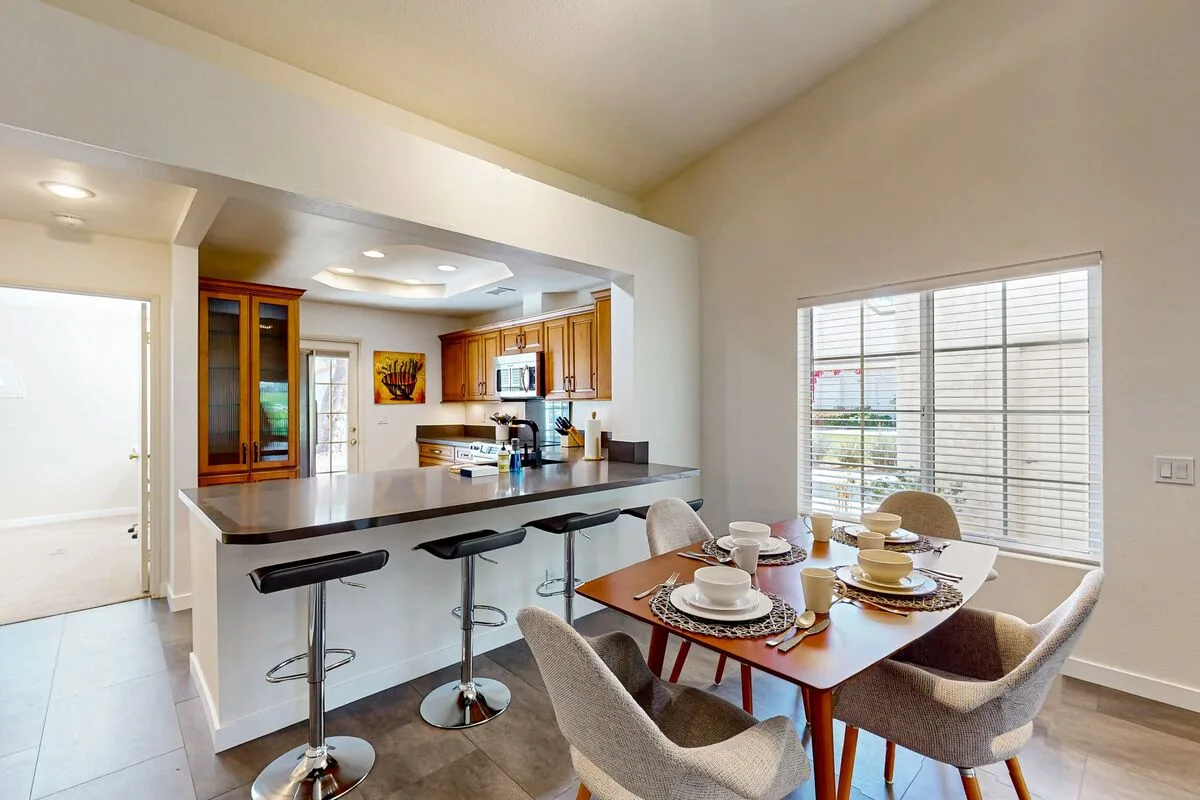 An open dining and kitchen area with a table set beside a breakfast bar.